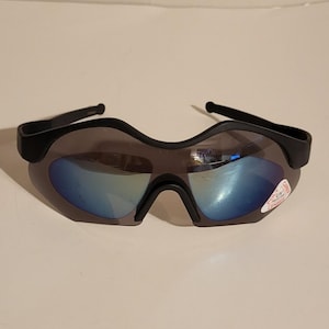 May include: Black sports sunglasses with blue mirrored lenses. The sunglasses have a curved, wraparound design and a small sticker on the right lens. The frame is black and the lenses reflect a blue hue.
