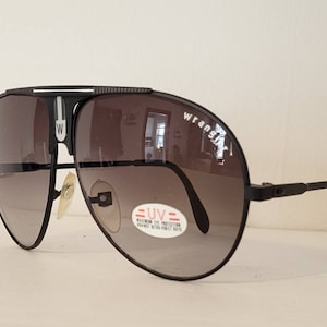 May include: Black Wrangler aviator sunglasses with gradient lenses. The sunglasses have a black frame with the Wrangler logo on the lens. A sticker on the lens reads "UV Maximum Eye Protection".