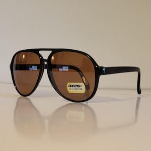 May include: A white ceramic mug with a black handle and the text "But First, Coffee" in a black, bold font. The mug is on a white surface.