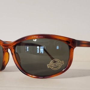 May include: Tortoise shell sunglasses with dark green lenses. The sunglasses have a "Maximum Ultra-Violet Protection" label on the right lens.