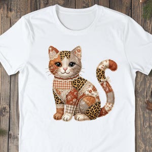Peut inclure: T-shirt blanc avec un motif de chat en patchwork. Le chat présente des motifs léopard, floraux et vichy dans des tons marron, orange et crème. Le chat est assis, la queue enroulée, créant une esthétique charmante.