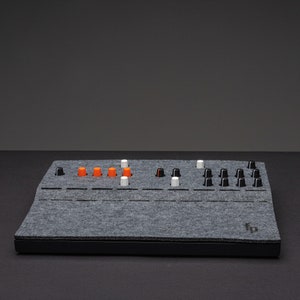 Könnte beinhalten: Ein grauer Filmmusikcontroller mit schwarzen Knöpfen und orangefarbenen und weißen Knöpfen. Der Controller hat eine schwarze Basis und der Text "fp" ist auf der rechten Seite aufgedruckt.