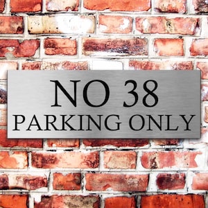May include: A silver metal sign with black text that reads "NO 38 PARKING ONLY".