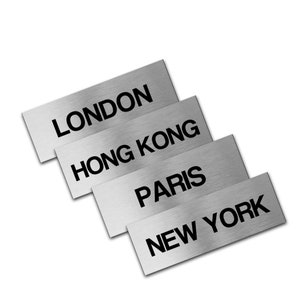 May include: Four silver metal plaques with the names of cities: London, Hong Kong, Paris, and New York.