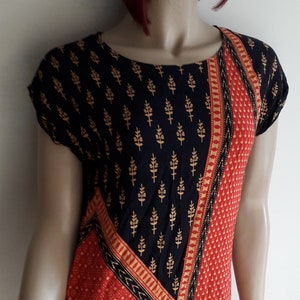 May include: A short-sleeved black and red dress with a geometric pattern. The dress has a black background with gold floral designs and a red section with a small white polka dot pattern.