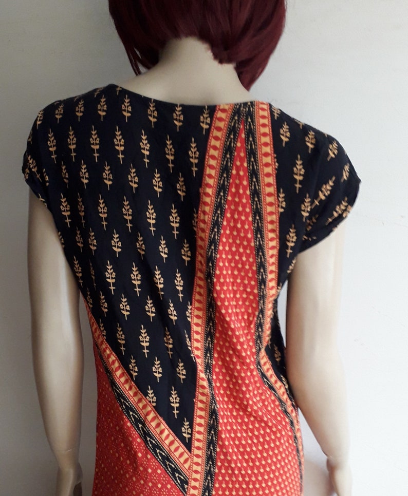 May include: A black and red dress with a geometric pattern and gold accents. The dress has short sleeves and a scoop neck.