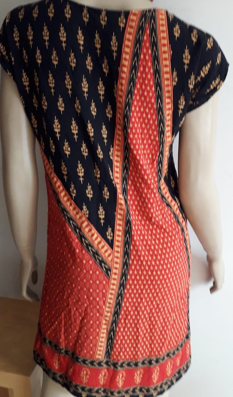 May include: Black and red patterned top with gold accents. The top has a scoop neck and short sleeves.