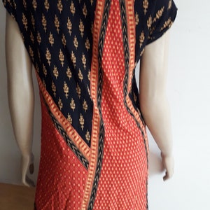 May include: A black and red patterned top with gold accents. The top has a scoop neck and short sleeves.