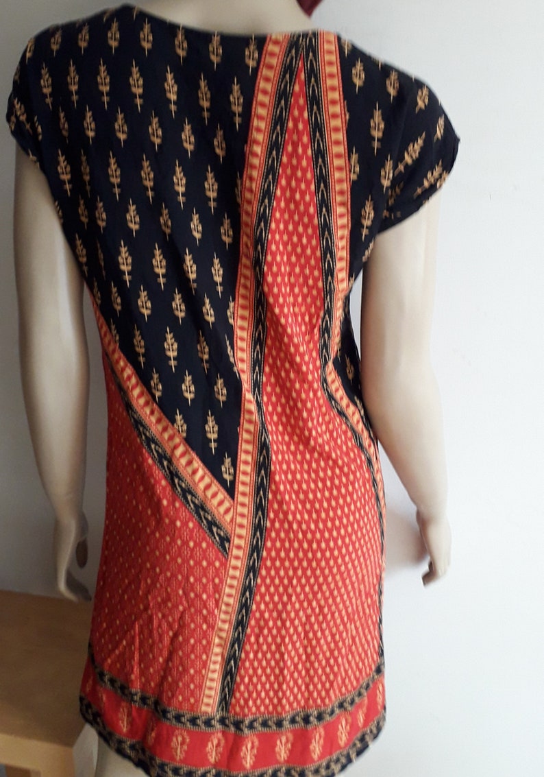 May include: A black and red patterned top with gold accents. The top has a scoop neck and short sleeves.