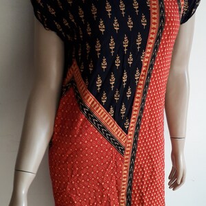 May include: A short-sleeved dress with a black and gold geometric pattern on the top half and a red and gold geometric pattern on the bottom half.