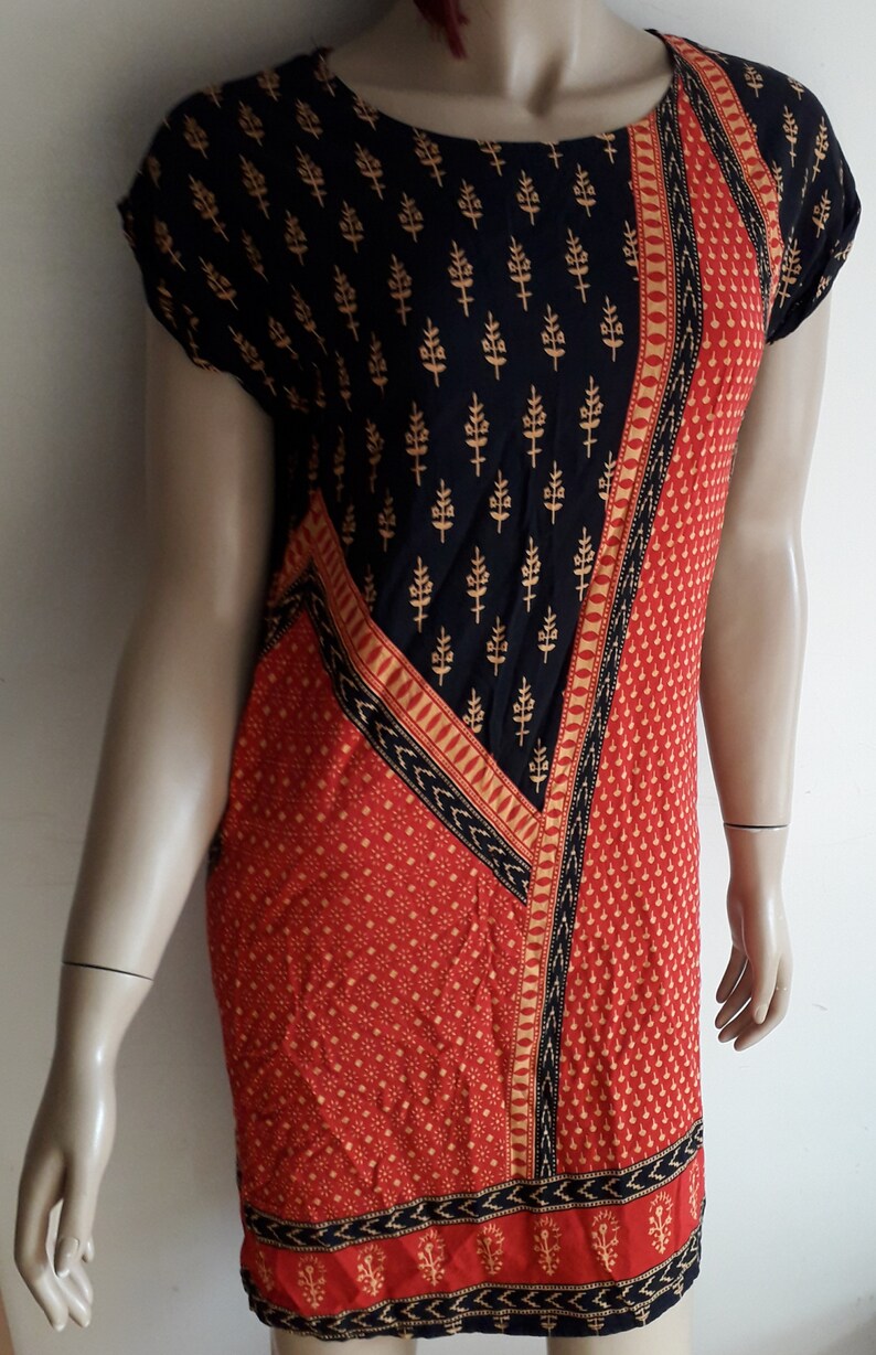 May include: A short-sleeved dress with a black and gold geometric pattern on the top half and a red and gold geometric pattern on the bottom half.