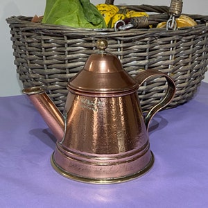 Op de afbeelding: Een koperen theepot met een messing band rond de bodem. De theepot heeft een gehamerde afwerking en een klein knopje op de deksel. De tekst "Old Paterson" is zichtbaar op de zijkant van de theepot.