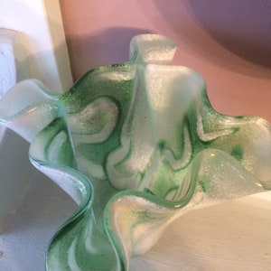May include: A green and white glass vase with a wavy, ruffled design. The vase has a textured, frosted finish.