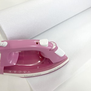 May include: A pink iron with a white handle and a white cord. The iron is on a white fabric roll. The iron has a button on the handle and a dial on the side. The iron has the text "LIGHT AND EASY" printed on the side. The iron also has the text "Russell Hobbs" printed on the side.