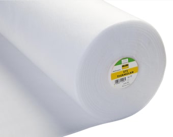 May include: A large roll of white Vlieseline 272 Thermolam batting fabric. The circular label on the end of the roll displays the text 272 THERMOLAM, 100% PES, and 90 cm x 25 m. The material has a soft, fibrous, and uniform texture throughout.