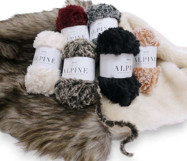 Pu&ograve; includere: Sei gomitoli di filato morbido e soffice in vari colori, tra cui bianco, nero, marrone, beige e bordeaux. Il filato &egrave; etichettato "ALPINE LUXE FUR EFFECT YARN" ed &egrave; mostrato su uno sfondo di pelliccia sintetica.