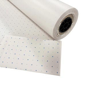 May include: A large roll of white paper featuring a repeating pattern of small blue cross symbols and tiny dots. The paper is tightly wound around a black plastic core, with a portion of the patterned sheet unrolled and laid flat in the foreground.