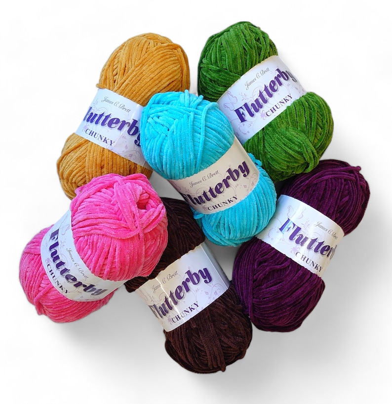 Pu&ograve; includere: Un assortimento di gomitoli di lana grossa e colorata, tra cui giallo senape, verde smeraldo, turchese, fucsia, marrone e viola. Ogni gomitolo ha un'etichetta con la scritta "Flutterby CHUNKY". Ideale per lavori a maglia e uncinetto.