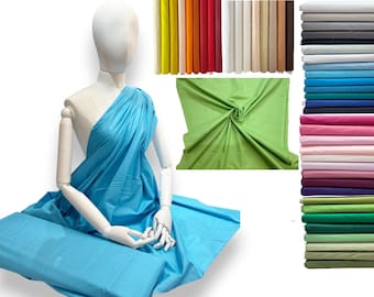 May include: A mannequin draped in light blue fabric, with additional rolls of fabric in various colors. Stacks of folded fabric in shades of blue, pink, green, and gray are also visible. The image showcases a variety of textiles.