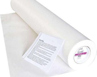 May include: A roll of white fusible interfacing with a sheet of the same material partially unrolled. A small white paper with instructions is next to the interfacing. The end of the roll has a pink and white label with the number 1152.