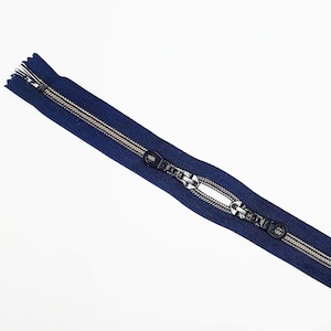 May include: A navy blue zipper with a gold metal slider and black plastic pull tabs.