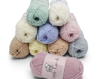 May include: A collection of pastel-colored yarn balls, including shades of blue, pink, yellow, and beige. One ball of yarn in the foreground has a label that reads "Little Lamb Double Knitting". The yarn is arranged in a pyramid shape.