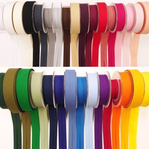 May include: A selection of bias tape spools in various colours, such as white, black, grey, brown, red, pink, green, blue, purple, orange, and yellow. The bias tape is well-arranged, with each spool displaying its colour.