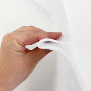 May include: White felt fabric, folded in half, showing the thickness and texture of the material.