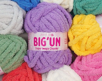 May include: A collection of colorful, super chunky yarn skeins. The central skein is purple, labeled "BIG'UN Super Mega Chunky." Surrounding skeins are in shades of blue, white, green, yellow, and pink. The yarn appears soft and plush, ideal for various crafting projects.