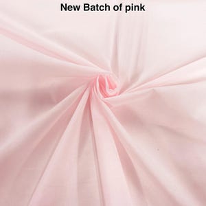 May include: A light pink fabric with a smooth texture, gathered in the center to create radiating folds. The text New Batch of pink is printed in black at the top center of the image, clearly visible against the pale pink background.