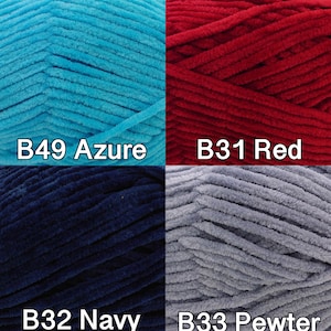 Pu&ograve; includere: Primo piano di quattro gomitoli di filato di peluche nei colori azzurro, rosso, blu navy e peltro. Ogni gomitolo &egrave; etichettato con un codice colore: B49 Azure, B31 Red, B32 Navy e B33 Pewter. Il filato appare morbido e strutturato, ideale per progetti di maglieria o uncinetto.