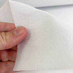 May include: White, soft, and fuzzy fabric with a textured surface. This fabric is commonly used for crafts and upholstery.