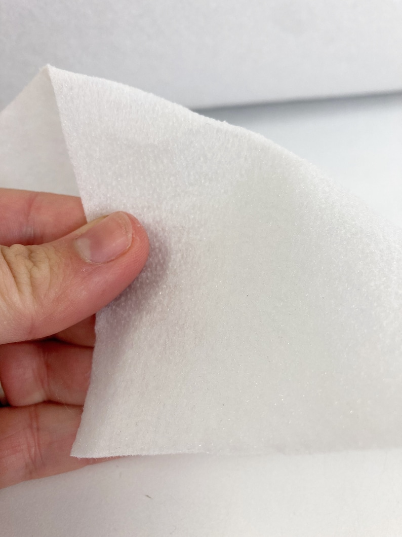 May include: White, soft, and fuzzy fabric with a textured surface. This fabric is commonly used for crafts and upholstery.
