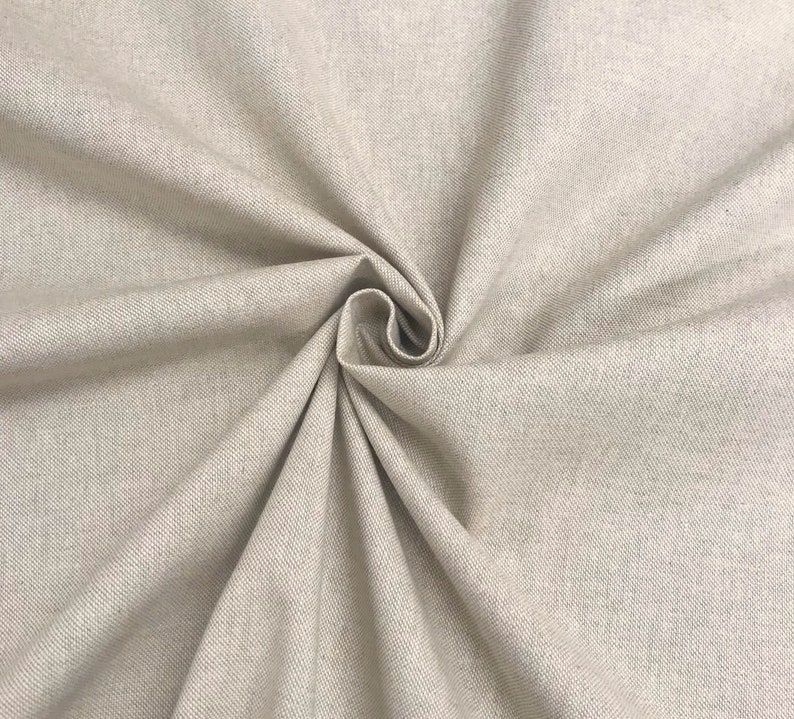 May include: Close-up of a beige fabric with a subtle texture. The fabric is folded and draped, showcasing its soft and smooth surface.