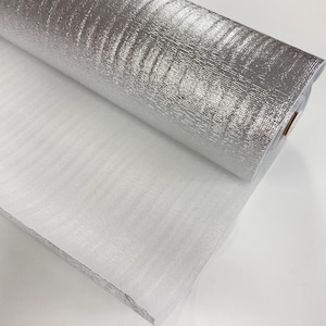May include: A roll of silver and white insulation material. The material is rolled up and the silver side is facing the camera. The white side is visible on the bottom of the roll.