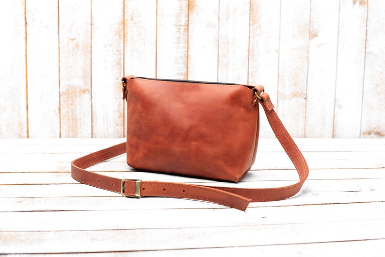 Peut inclure: Un sac &agrave; bandouli&egrave;re en cuir marron avec une longue sangle r&eacute;glable. Le sac a un design simple et est fait de cuir de haute qualit&eacute;.