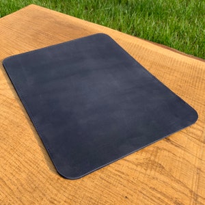May include: A dark blue leather desk mat. The mat is rectangular and has a smooth surface.