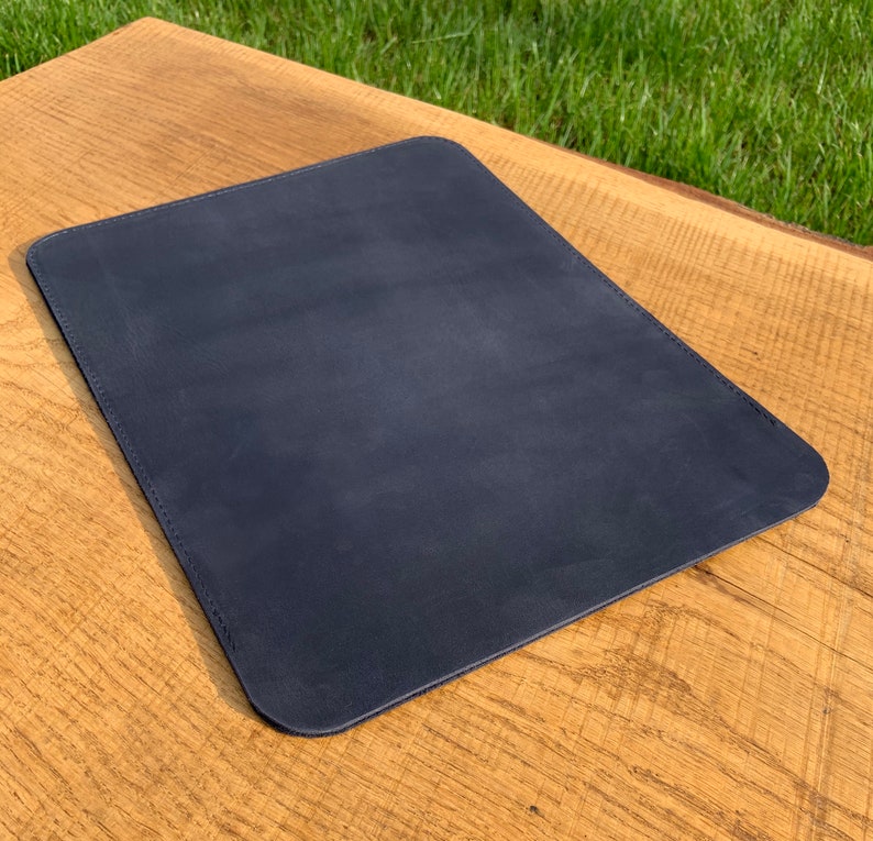 May include: A dark blue leather desk mat. The mat is rectangular and has a smooth surface.