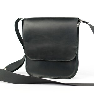 May include: A black leather shoulder bag with a flap closure and adjustable strap.