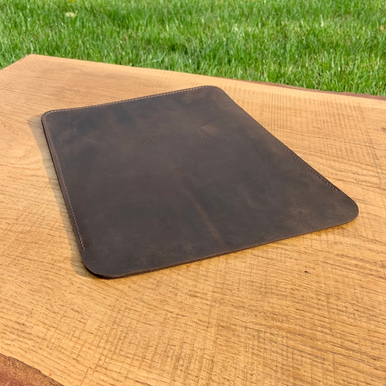 May include: A brown leather desk mat with a stitched edge.