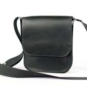 May include: A black leather shoulder bag with a flap closure and adjustable strap.