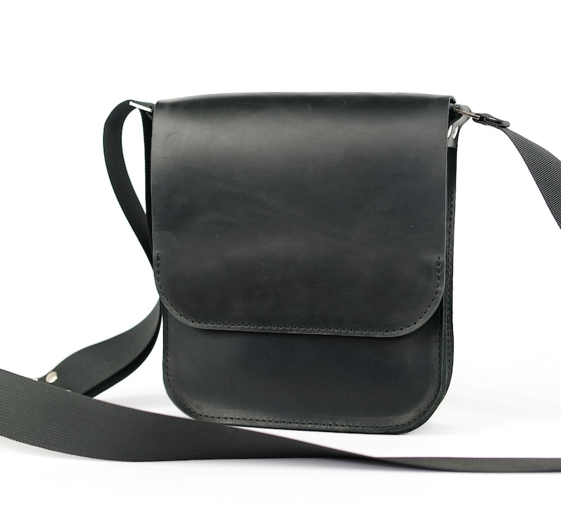 May include: A black leather shoulder bag with a flap closure and adjustable strap.