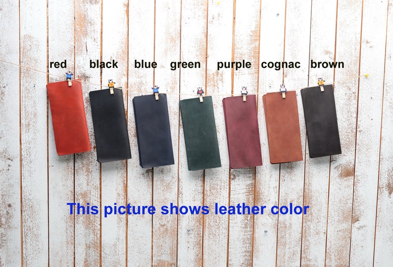 Peut inclure: Huit &eacute;chantillons de cuir suspendus &agrave; des pinces &agrave; linge sur un fond de bois blanc. Les &eacute;chantillons sont &eacute;tiquet&eacute;s avec les couleurs&nbsp;: rouge, noir, bleu, vert, violet, cognac et marron.
