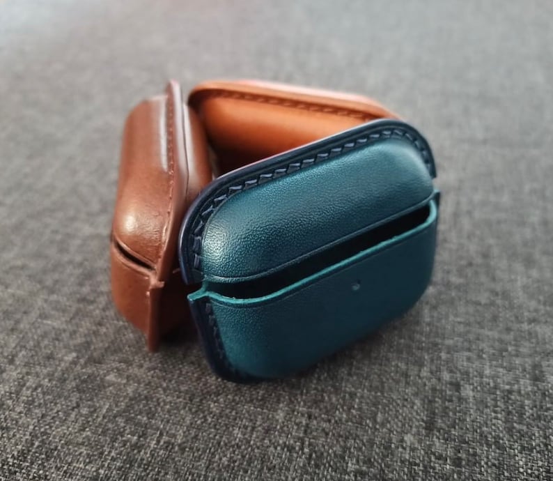 Puede incluir: Dos estuches protectores para auriculares inal&aacute;mbricos. Un estuche es de cuero marr&oacute;n y el otro de cuero azul.