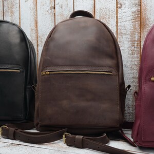 Pu&ograve; includere: Tre zaini in pelle di diversi colori: nero, marrone e bordeaux. Gli zaini hanno una tasca con cerniera sul davanti e spallacci regolabili.