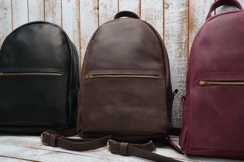 Pu&ograve; includere: Tre zaini in pelle di diversi colori: nero, marrone e bordeaux. Gli zaini hanno una tasca con cerniera sul davanti e spallacci regolabili.