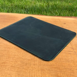 May include: A dark green leather desk mat with a stitched edge.