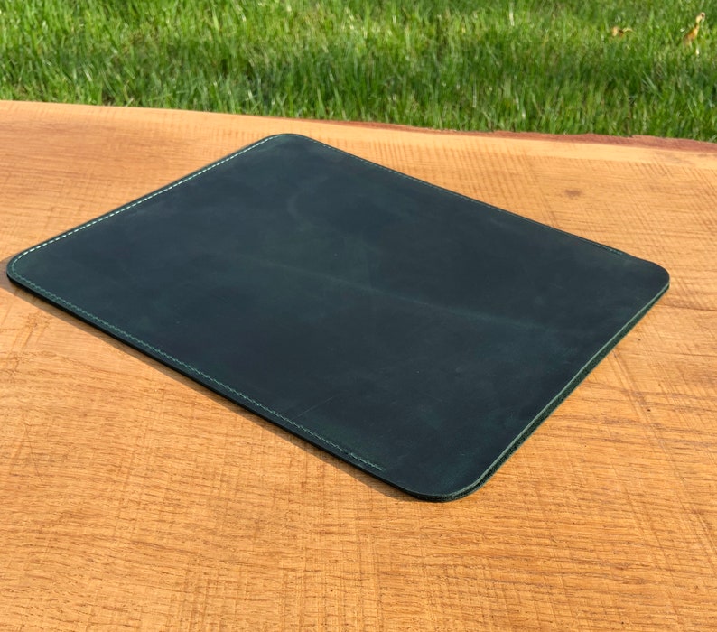 May include: A dark green leather desk mat with a stitched edge.