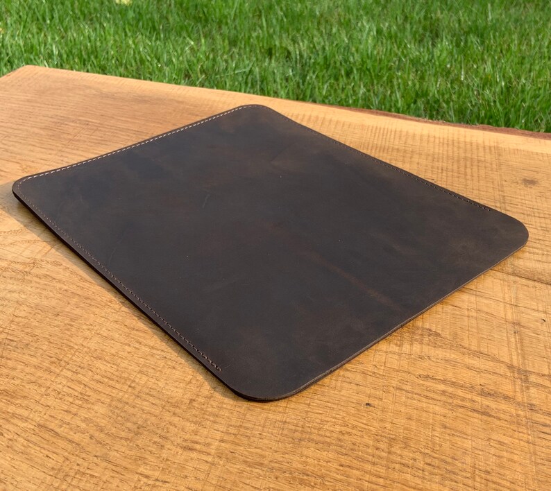 May include: A dark brown leather desk mat with stitched edges.
