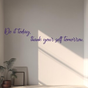 May include: An interior shot of a white room with a concrete floor and a potted plant. The wall features the text "Do it today, thank your self tomorrow" in a purple script. A framed artwork leans against the wall.